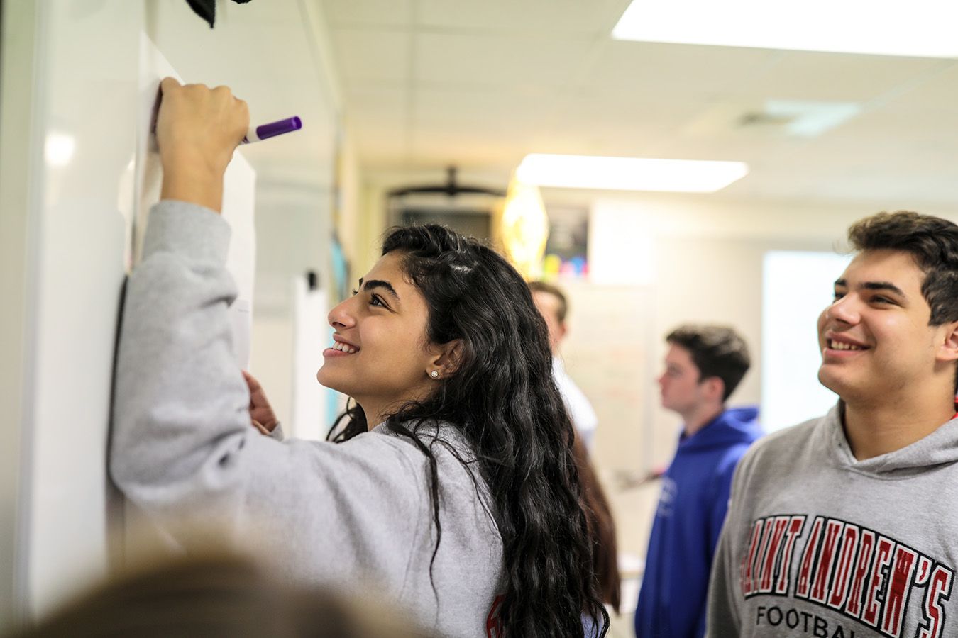 Eine Schülerin schreibt etwas an ein Whiteboard